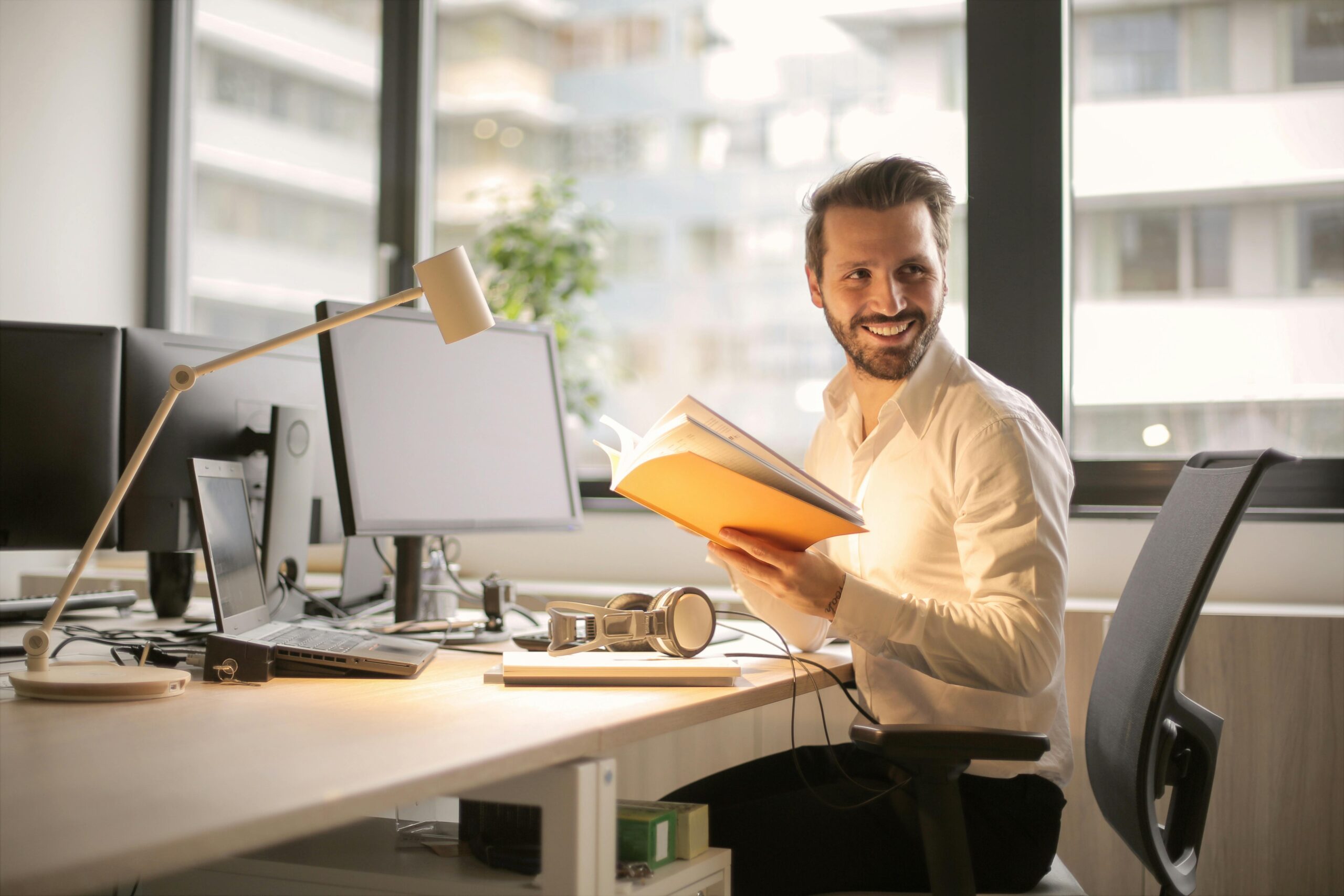 Man reading book at computer